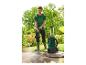 Homme dans un jardin utilisant un nettoyeur haute pression pour nettoyer une terrasse.