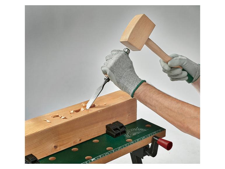 Un homme utilise un ciseau et un marteau pour travailler le bois.