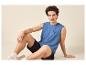 Jeune homme en débardeur bleu avec imprimé 'SURFING VIBE' et short noir.