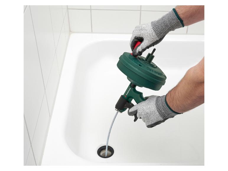 Homme ganté utilisant un déboucheur manuel dans une baignoire.