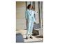 Une femme en tailleur-pantalon bleu clair regarde sa montre.