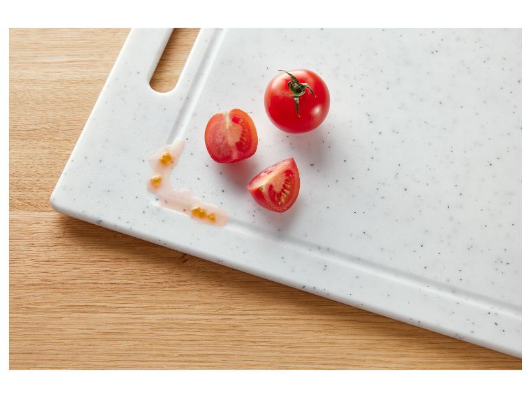 Tomates fraîches, entières et coupées, sur une planche à découper blanche, avec du jus de tomate