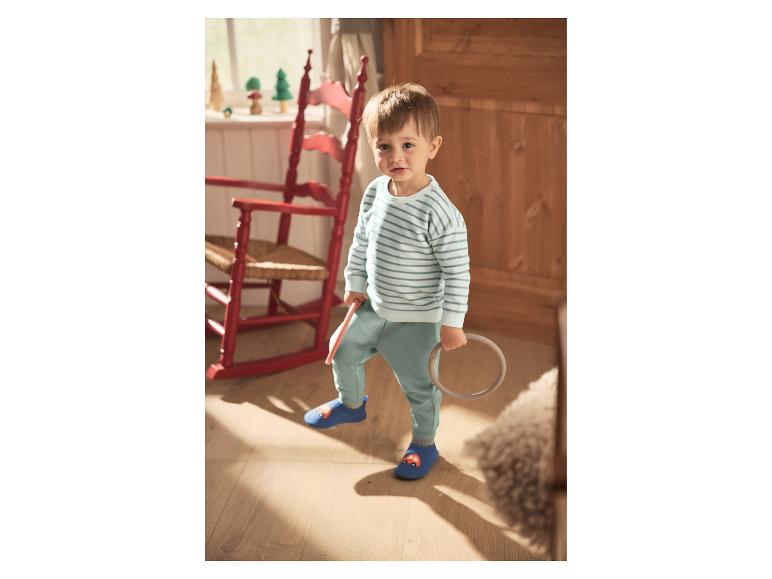 Tout-petit portant des chaussons pour bébé LUPILU® avec un motif de voiture