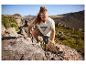 Homme en t-shirt et short de sport escaladant des rochers en montagne.