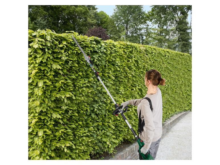 Une femme utilise une taille-haie STIHL longue pour tailler une haie haute.