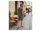 Homme en t-shirt vert imprimé palmier et short gris marchant dans une rue.