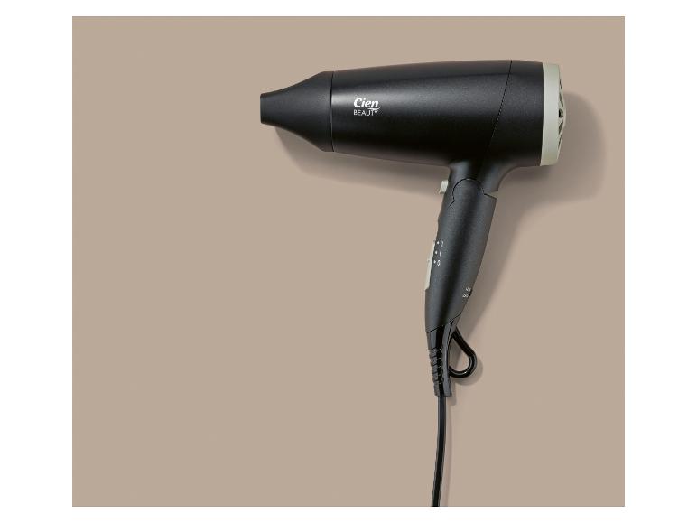 Sèche-cheveux noir avec des détails gris sur fond beige.
