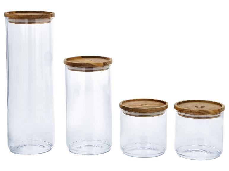 Ensemble de quatre bocaux de rangement transparents avec couvercles en bois, de différentes hauteurs.