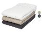 Piles de draps-housses en blanc, beige et gris foncé avec des échantillons de couleur.