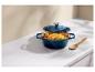 Cocotte bleue avec poulet rôti et légumes sur un comptoir blanc.