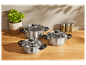 Trois casseroles en acier inoxydable avec couvercles en verre sur un comptoir en bois.