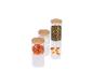 Trois pots en verre avec des couvercles en bois, remplis de pistaches et d'abricots secs.