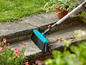 Un balai bleu à long manche pour nettoyer les trottoirs.