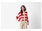 Femme en cardigan tricoté à rayures rouges et blanches et pantalon beige