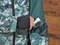 Une veste verte à imprimé camouflage, avec une carte blanche dans la poche.