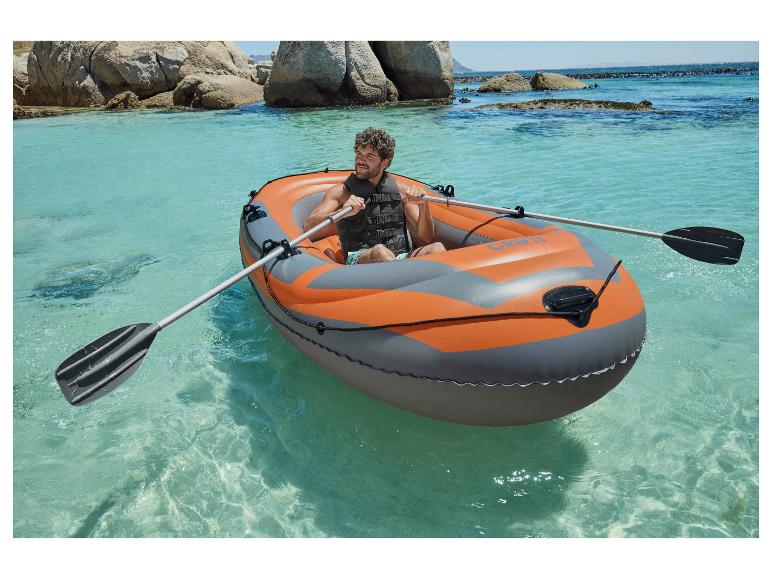 Un homme rame dans un bateau gonflable CRIVIT dans une eau claire.