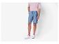Homme portant un t-shirt rose, un short bleu et des baskets blanches.