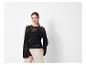 Pull noir ajouré et pantalon beige pour femme.