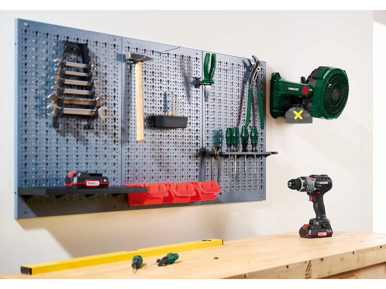 Panneau perforé avec outils d'atelier, y compris clés, marteau, tournevis et perceuse sans fil.