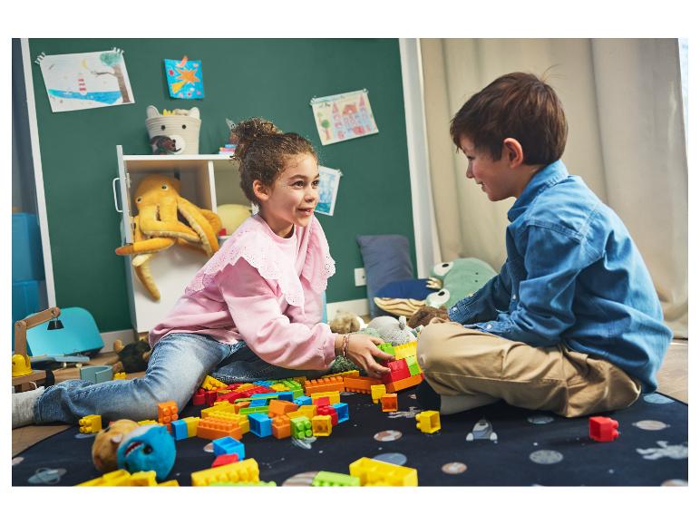 Deux enfants jouent avec des blocs LEGO colorés sur un tapis.