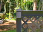 Une clôture en bois gris foncé avec un motif de grille diagonale.