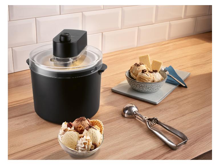 Machine à glace avec deux bols de glace, gaufrettes et cuillère sur un plan de travail en bois.