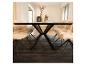 Salle à manger avec une table en bois noir et six chaises rembourrées beiges sur un tapis foncé.