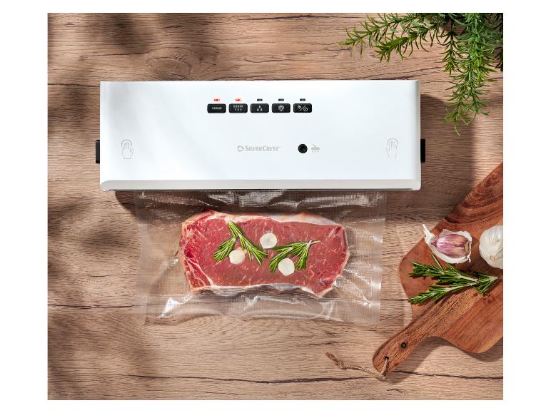 Machine sous vide SilverCrest avec steak, romarin et ail sur une table en bois.