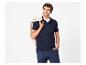 Homme en polo bleu marine et pantalon bleu, avec une veste beige sur l'épaule.