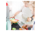 Des enfants jouent avec un jouet de cuisine en bois, simulant un barbecue avec des hamburgers et d'autres aliments en feutre.