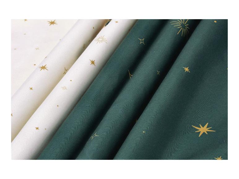 Tissus blancs et vert foncé avec des imprimés dorés d'étoiles et de feux d'artifice.