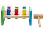 Un marteau en bois jouet et un jeu avec des chevilles de couleurs à frapper.