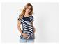 Femme enceinte souriante en haut de maternité rayé et jean, tenant son ventre.
