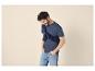 Homme en t-shirt bleu, pull bleu foncé noué sur les épaules et jean clair.