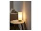 Une lampe de table blanche sur une table d'appoint ronde en bois.