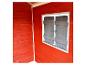 Intérieur d'une cabane de jeu en bois rouge avec une fenêtre et des volets gris