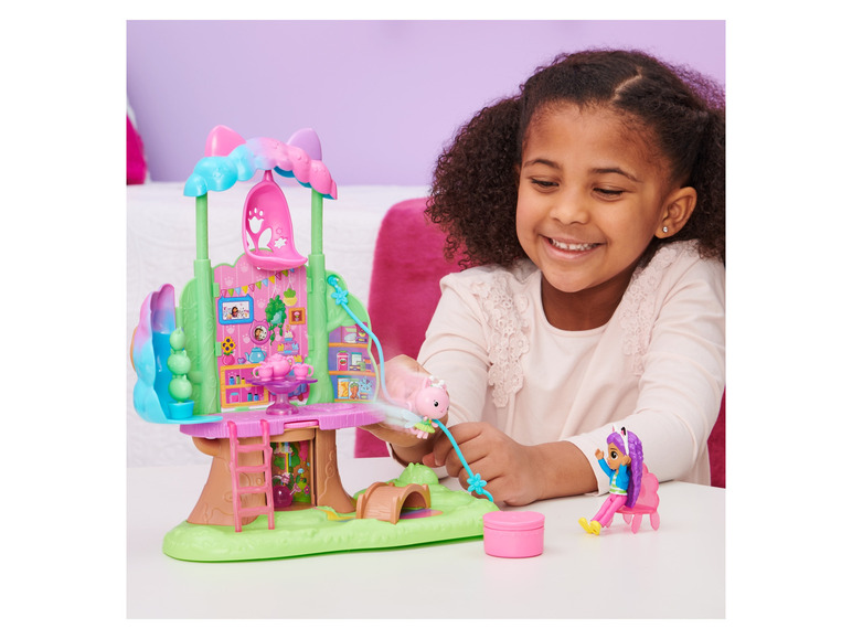 Une fille joue avec un set de jeu de maison dans les arbres et des poupées