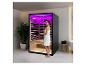 Femme entrant dans un sauna infrarouge avec éclairage violet dans une salle de bain moderne.