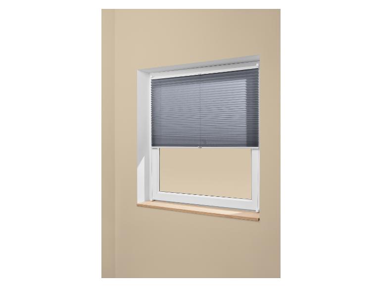 Store vénitien plissé gris sur une fenêtre blanche avec un rebord en bois.