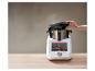 Un appareil de cuisine intelligent avec un écran affichant une recette de dessert, avec de la vapeur s'échappant de la marmite.