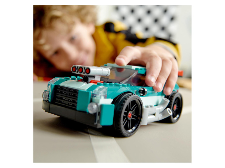 Un enfant joue avec une voiture LEGO verte.