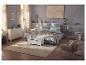 Chambre avec lit, commode, fauteuil et tapis dans des tons gris et beige.