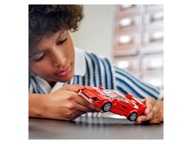 Un enfant tient un LEGO Ferrari F40 rouge.