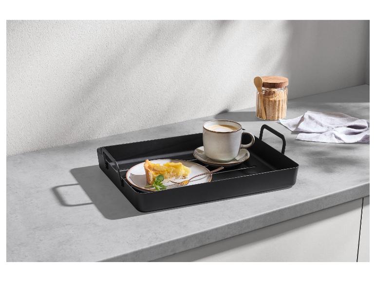 Plateau noir avec une tasse de café et une part de tarte sur un comptoir de cuisine.