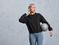 Une femme en sweat-shirt noir et leggings gris tenant un ballon de fitness Crivit.