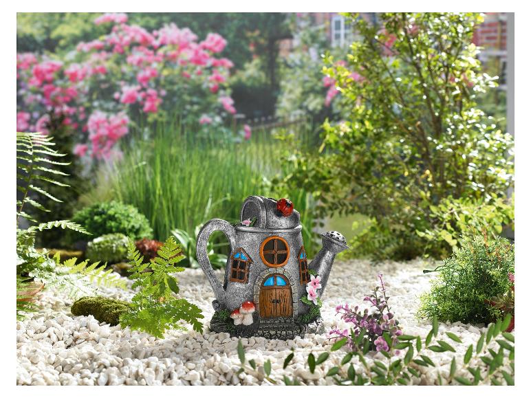 Une charmante maison de jardin en forme d'arrosoir, avec une coccinelle sur le toit.