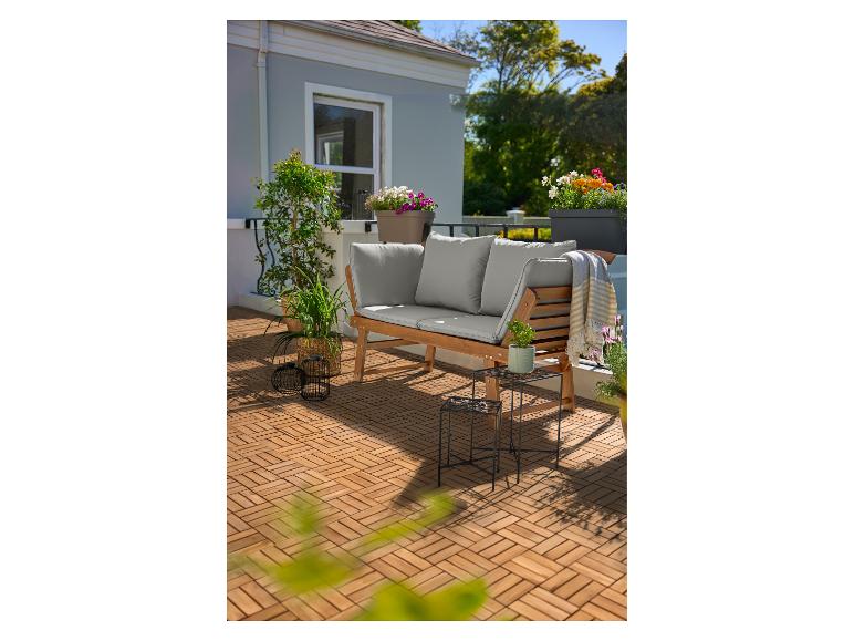Terrasse en bois avec un banc en bois et coussins gris, plantes et fleurs en pot.
