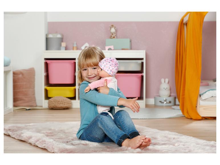 Fille souriante avec une poupée Baby Annabell dans une chambre d'enfant avec un tapis rose.