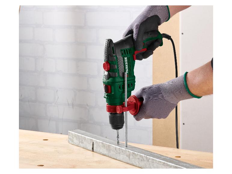 Homme ganté utilise une perceuse à percussion PARKSIDE pour percer une poutre métallique.