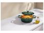 Cocotte en fonte verte avec poulet rôti et légumes sur un comptoir.